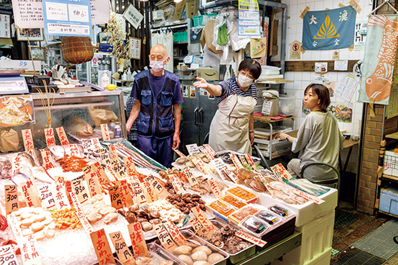 『鮮魚 木村』の店先で地元の人と交流する店主夫妻と女性客