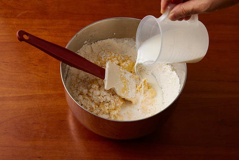 小麦粉を入れたボウルに牛乳を加えている写真