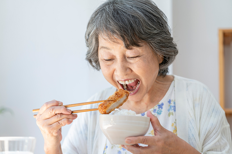 揚げ物を食べるシニア女性