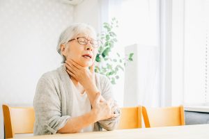のどをさわって苦しそうな女性
