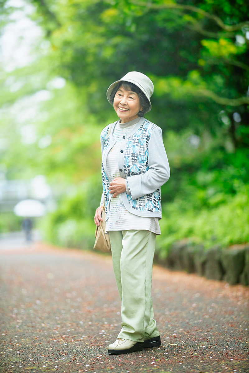 緑を背景に佇むシニア女性