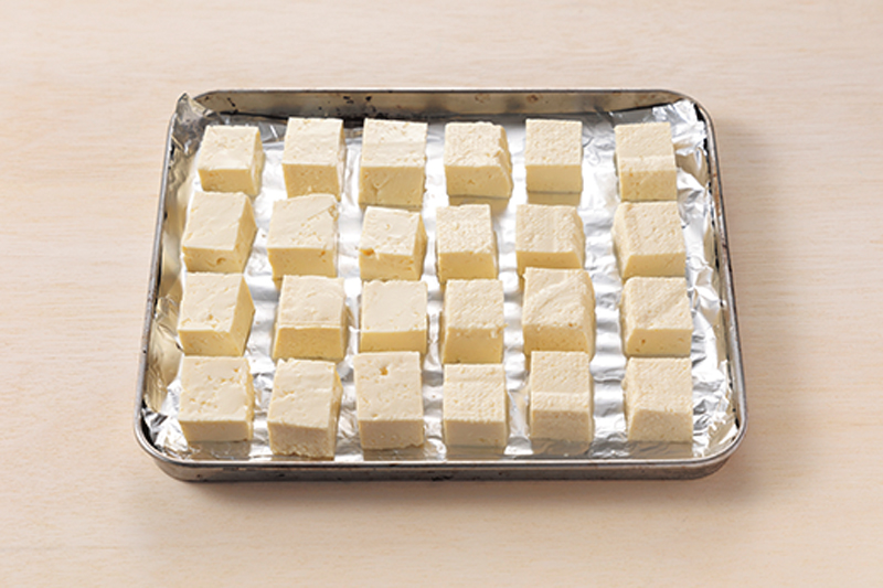 【1】木綿豆腐を2～2.5cm角に切りアルミホイルを敷いたトースターの天板に並べる。