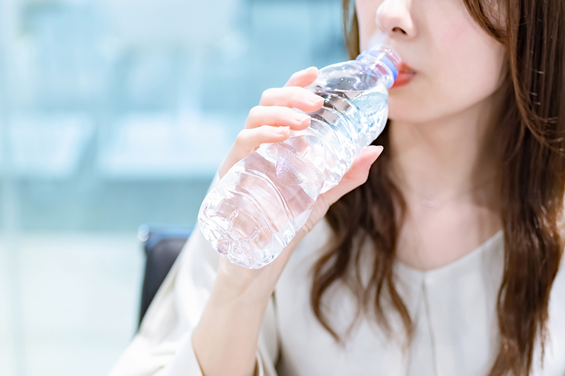 ペットボトルの水を飲む女性