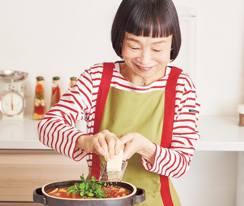 すりおろしたパルメザンチーズをトッピングする竹原芳子さん