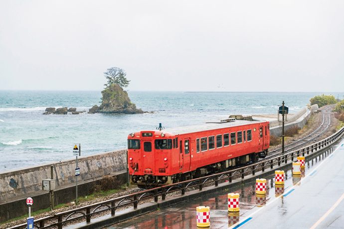 海沿いを赤い電車が走る雨晴（あまはらし）海岸