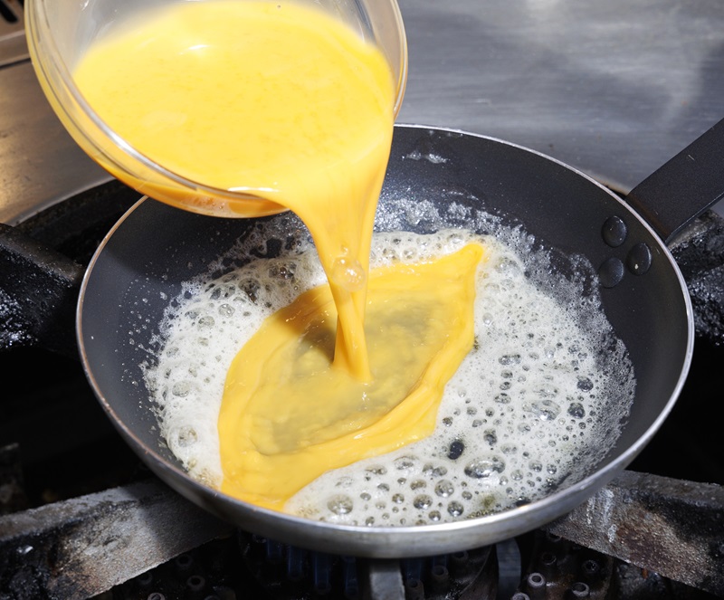 バターを熱したフライパンに卵の半量を流し入れる