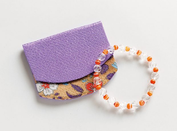 手首につける透明な石とオレンジ色の石の念珠と紫色と花柄の念珠入れ