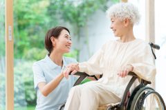 young asian caregiver and senior woman riding wheelchair