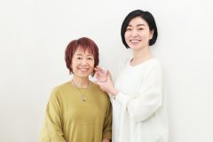 うぐいす色の服を着た女性と白い服を着た女性