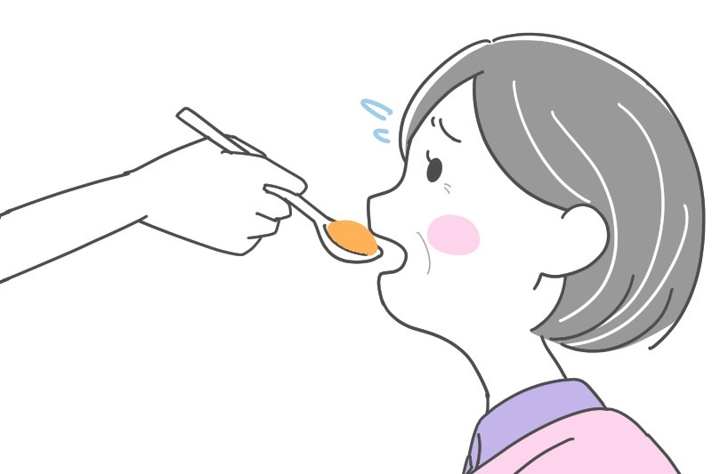 斜め上からスプーンを口に入れている