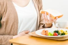 食事を前に胃を押さえる人